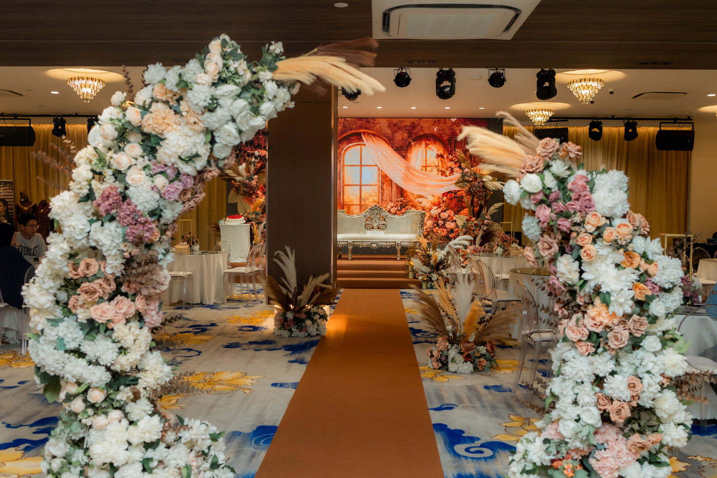 Floral arch and carpeted aisle leading to the stage